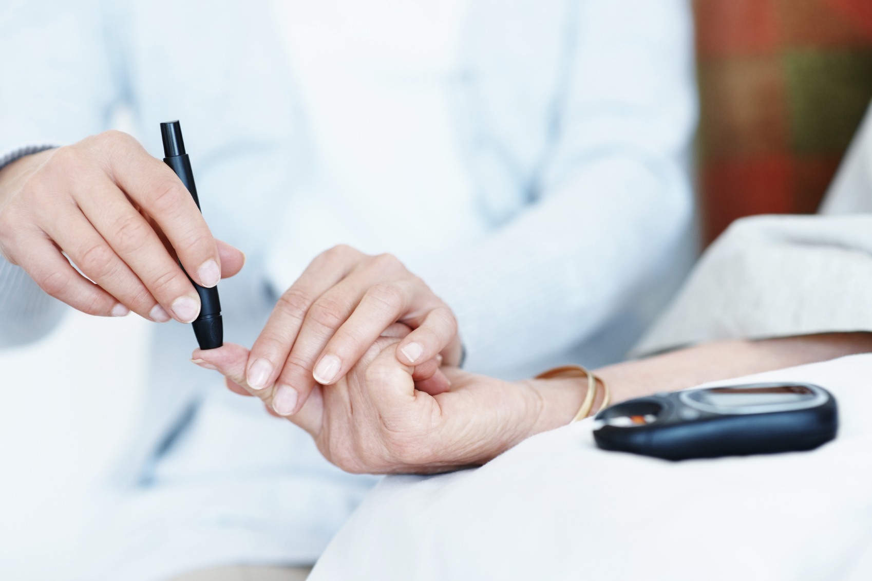 An elderly woman receiving an injection in her finger to check her blood sugar levels
